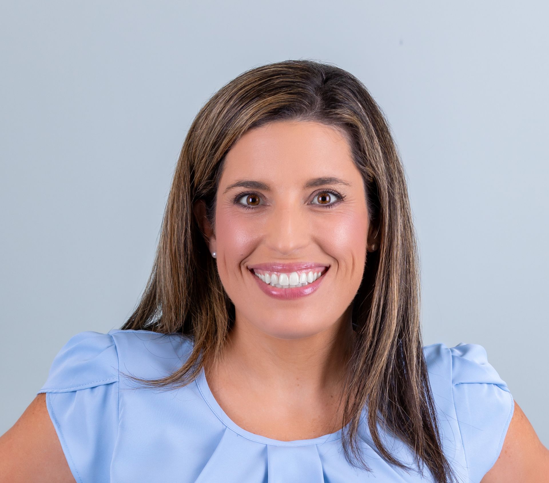 A woman in a blue shirt is smiling for the camera.