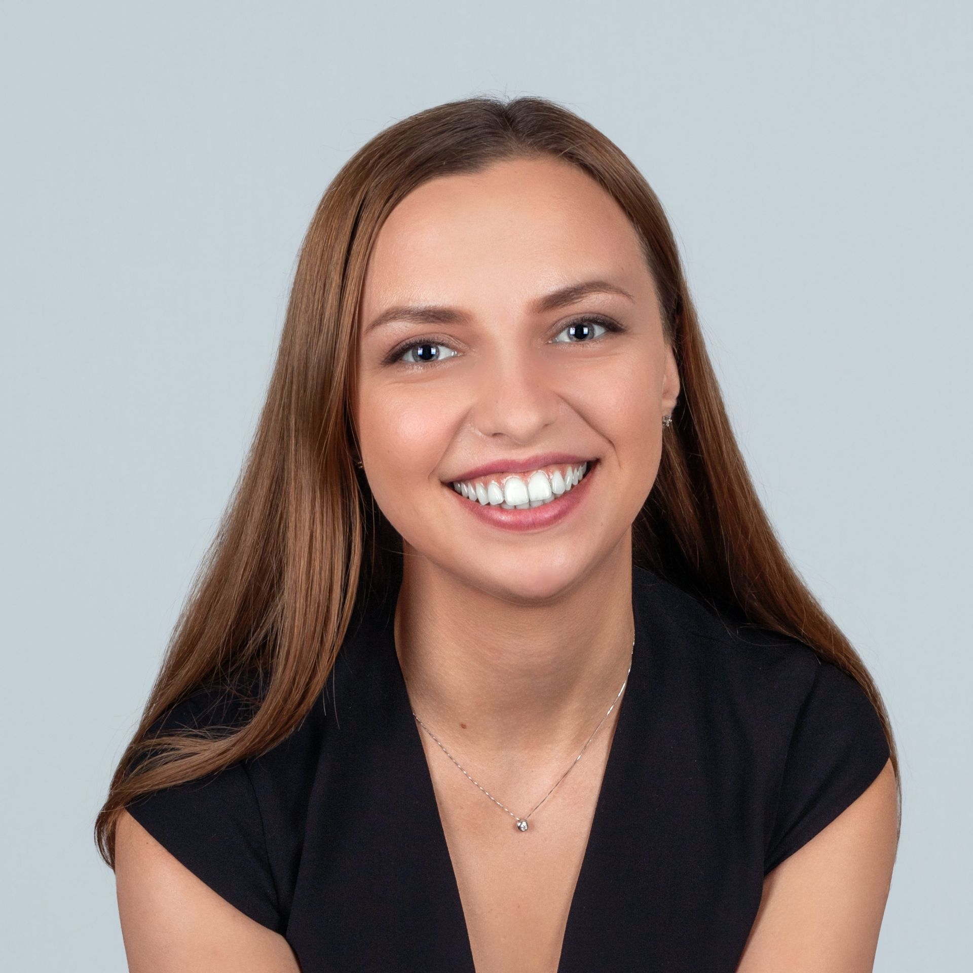 A woman wearing a black shirt and a necklace is smiling for the camera.