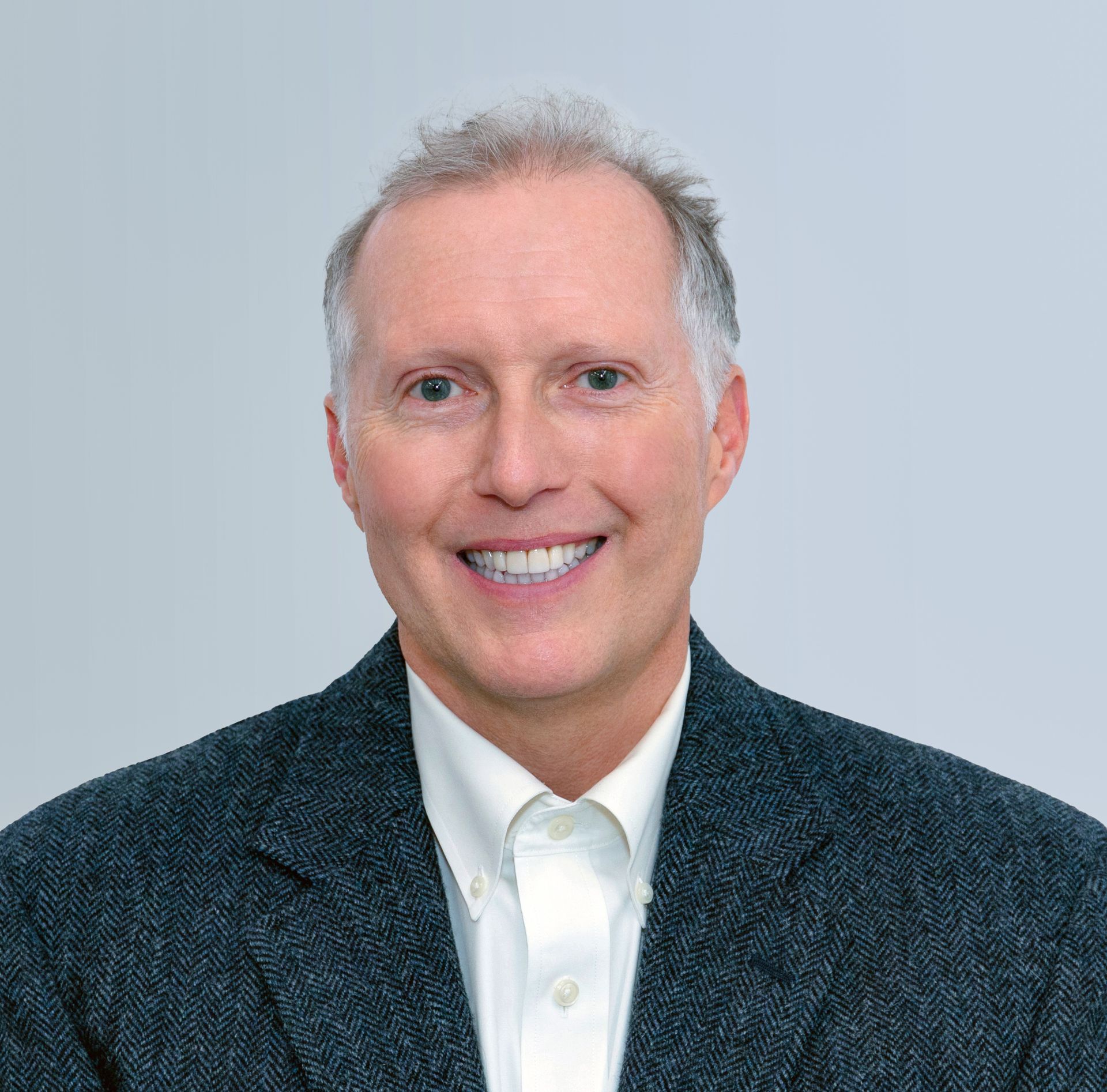 A man in a suit and white shirt is smiling for the camera.