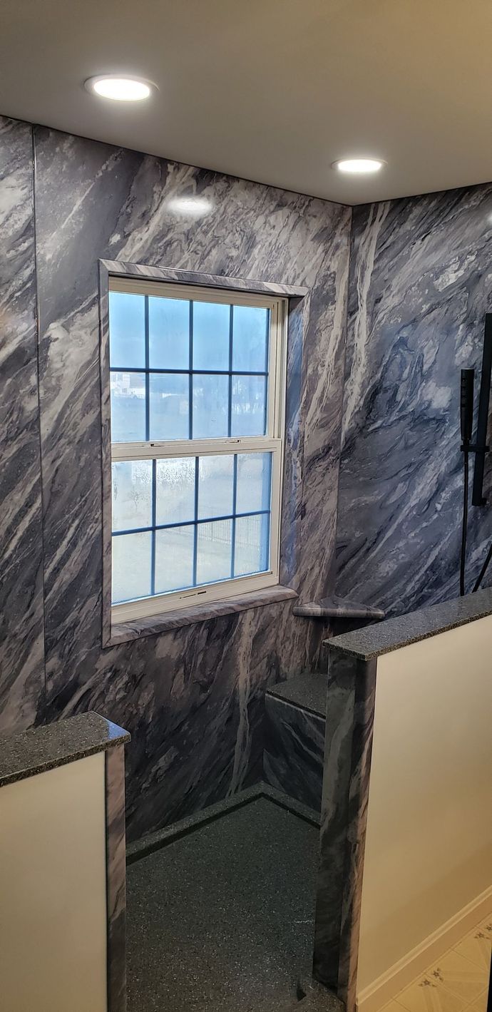 A bathroom with marble walls and a window.