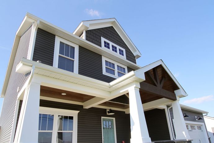 A large house with a porch and a blue sky in the background