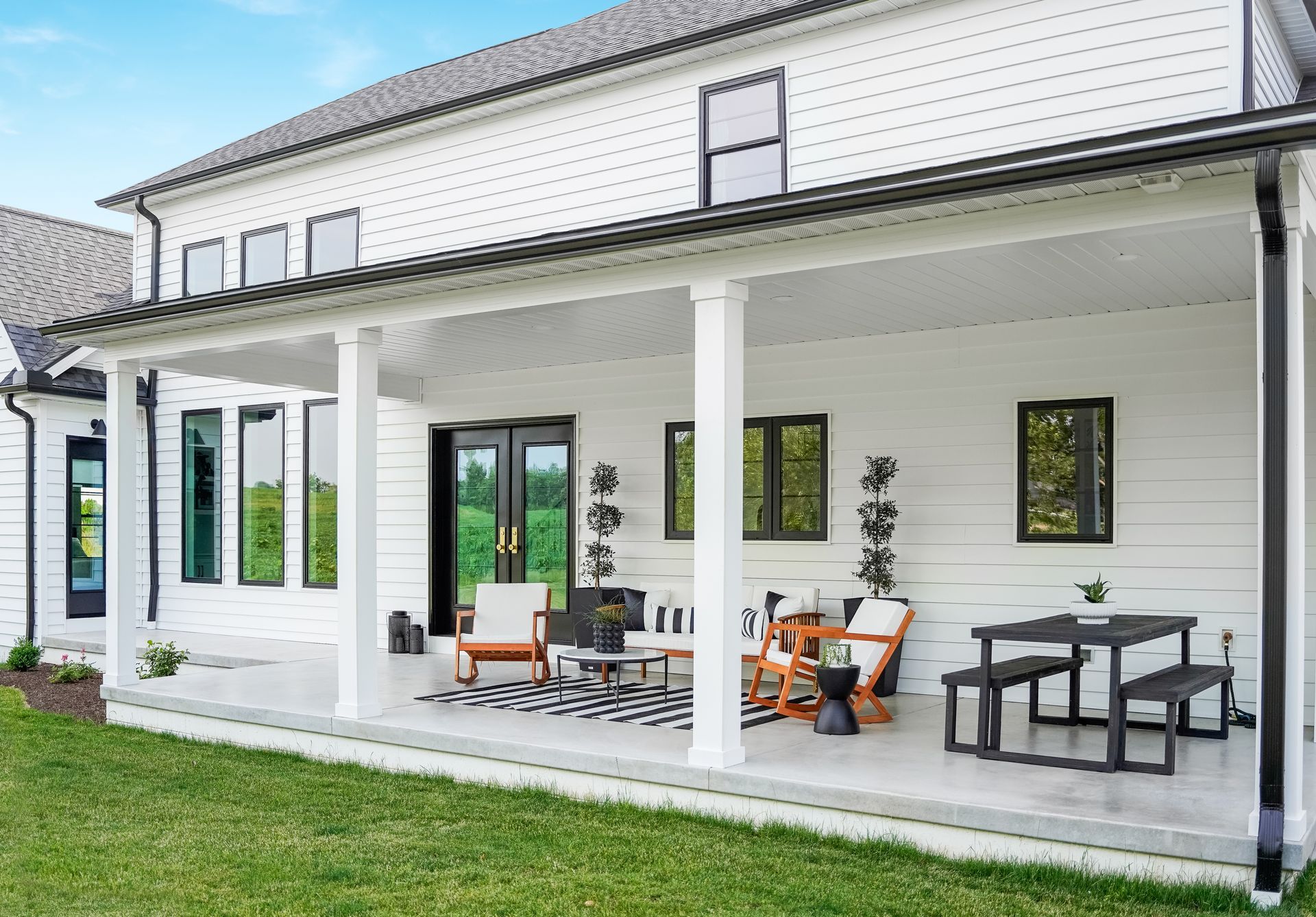 A white house with a large porch and patio furniture.