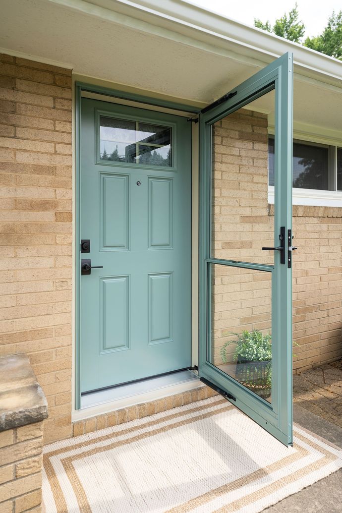 The front door of a brick house with a blue door and sliding glass doors.