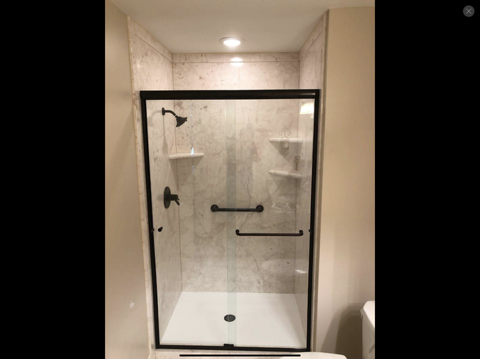 A bathroom with a sliding glass shower door and a toilet.