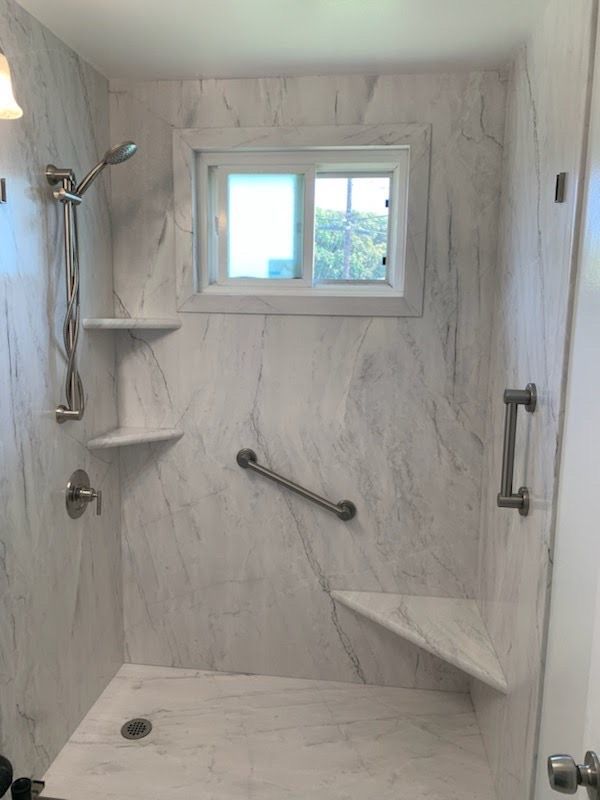 A shower with a window and a handle on the wall.