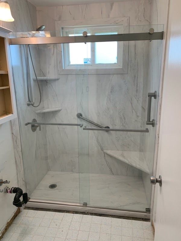 A bathroom with a sliding glass shower door and a window.