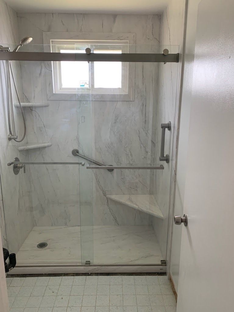 A bathroom with a sliding glass shower door and a window.