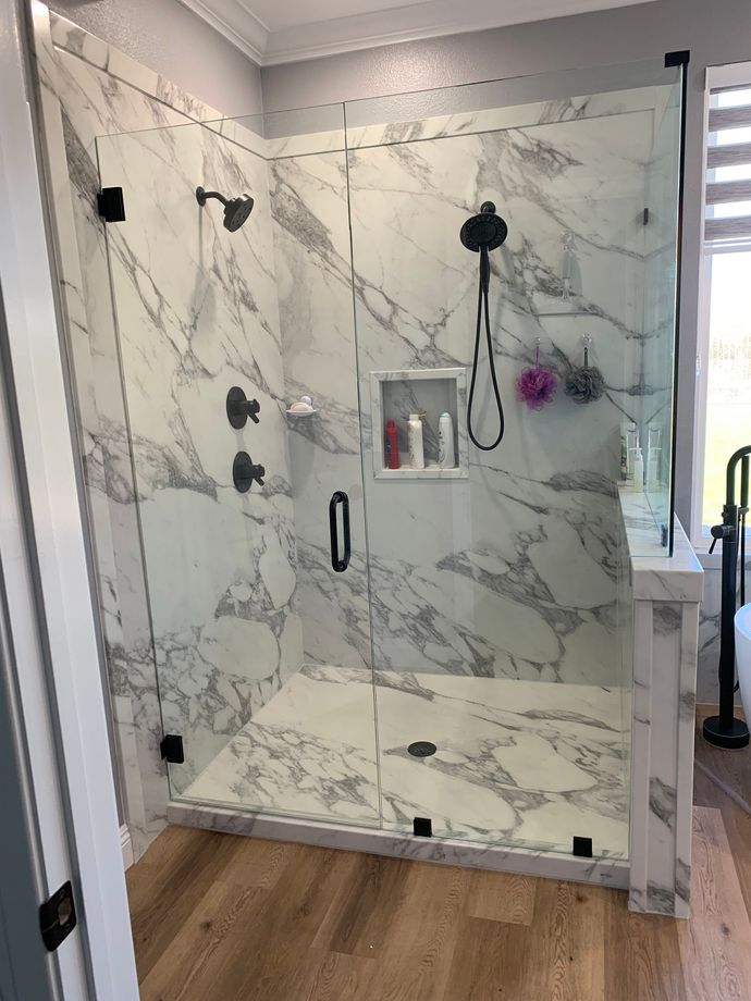 A bathroom with marble tiles and a walk in shower with a glass door.