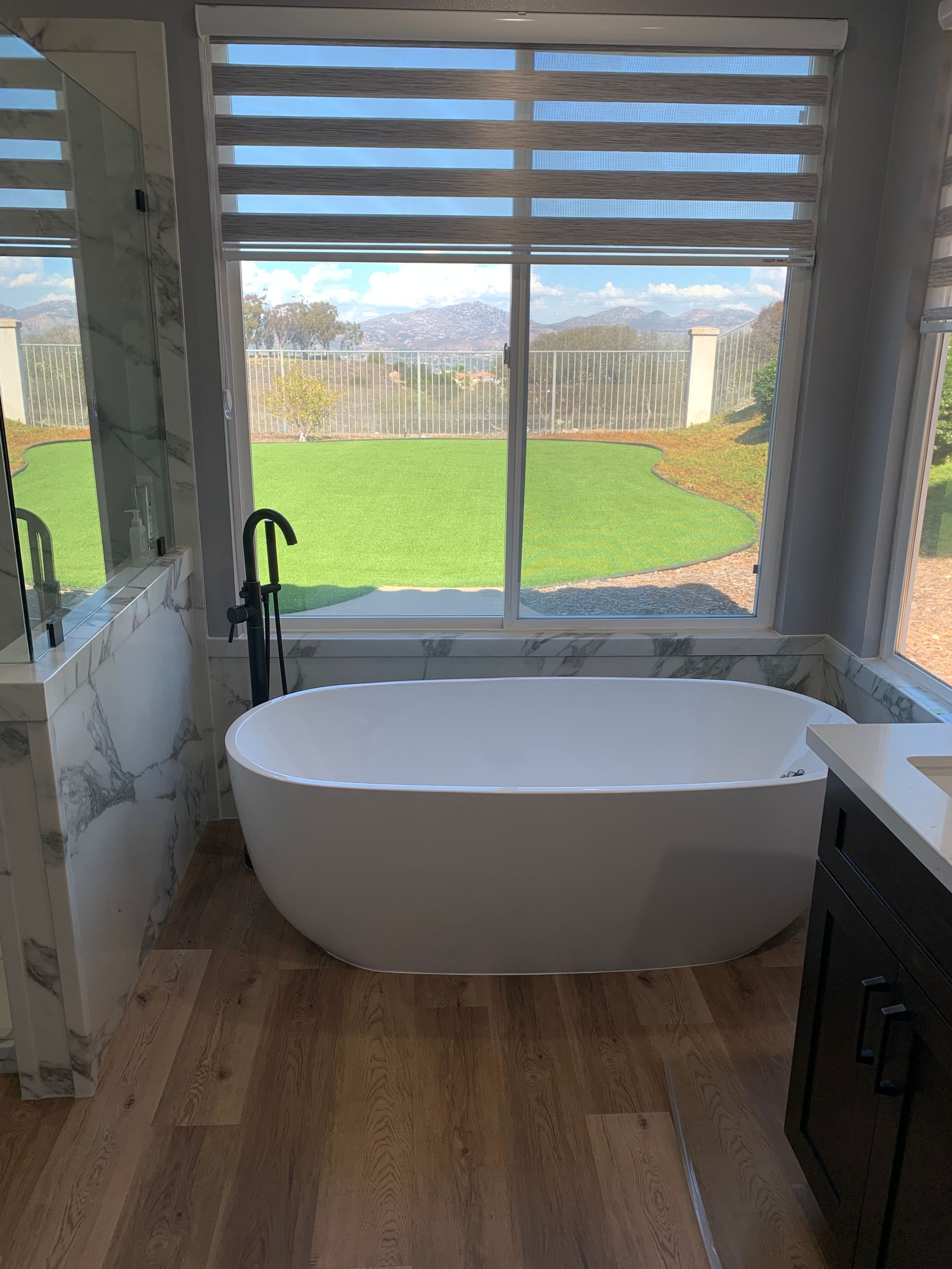 A bathroom with a large tub and a large window.