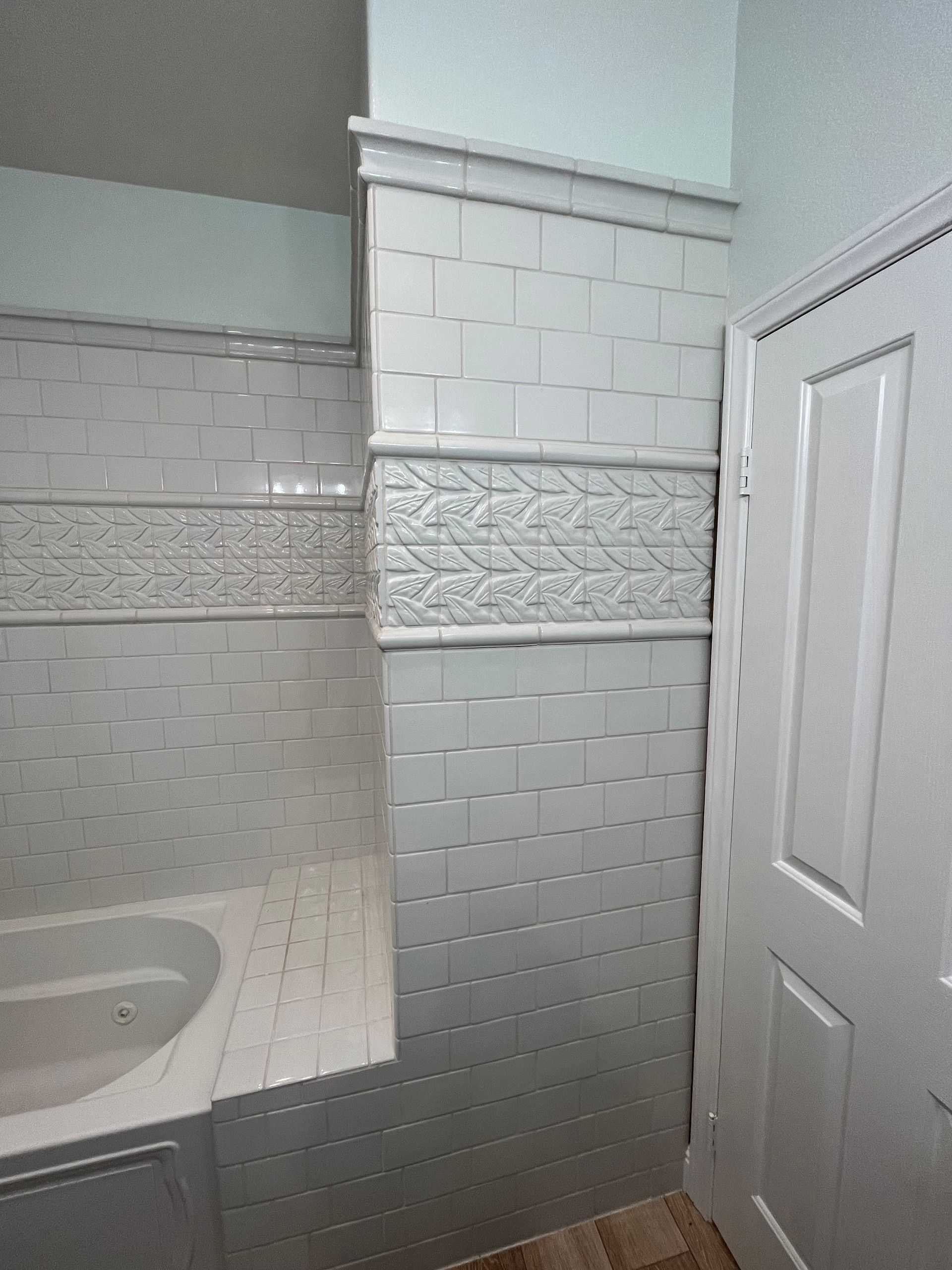 A bathroom with white tiles and a bathtub