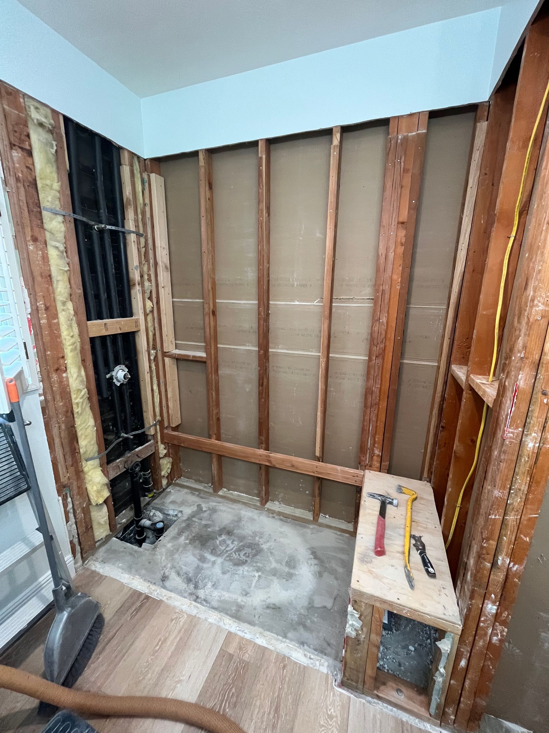 A bathroom under construction with wooden walls and a wooden bench with tools on it.