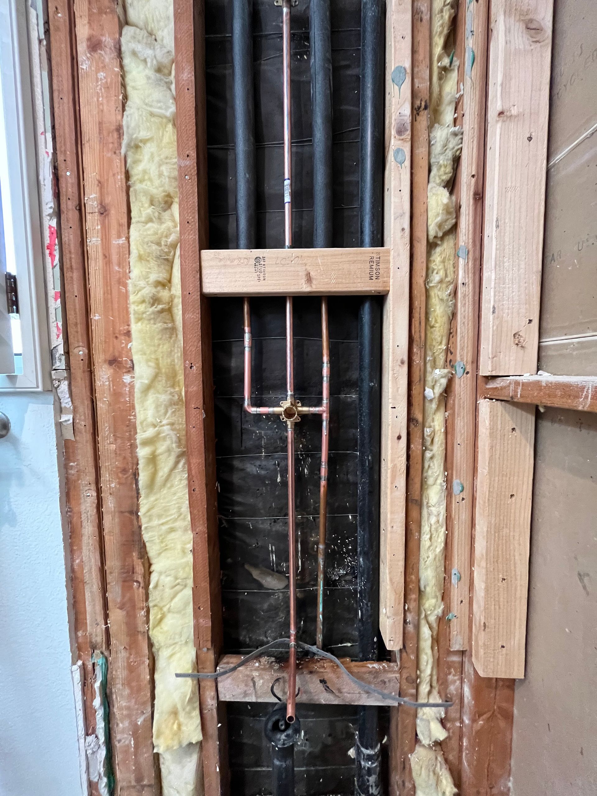 A wooden wall with copper pipes coming out of it