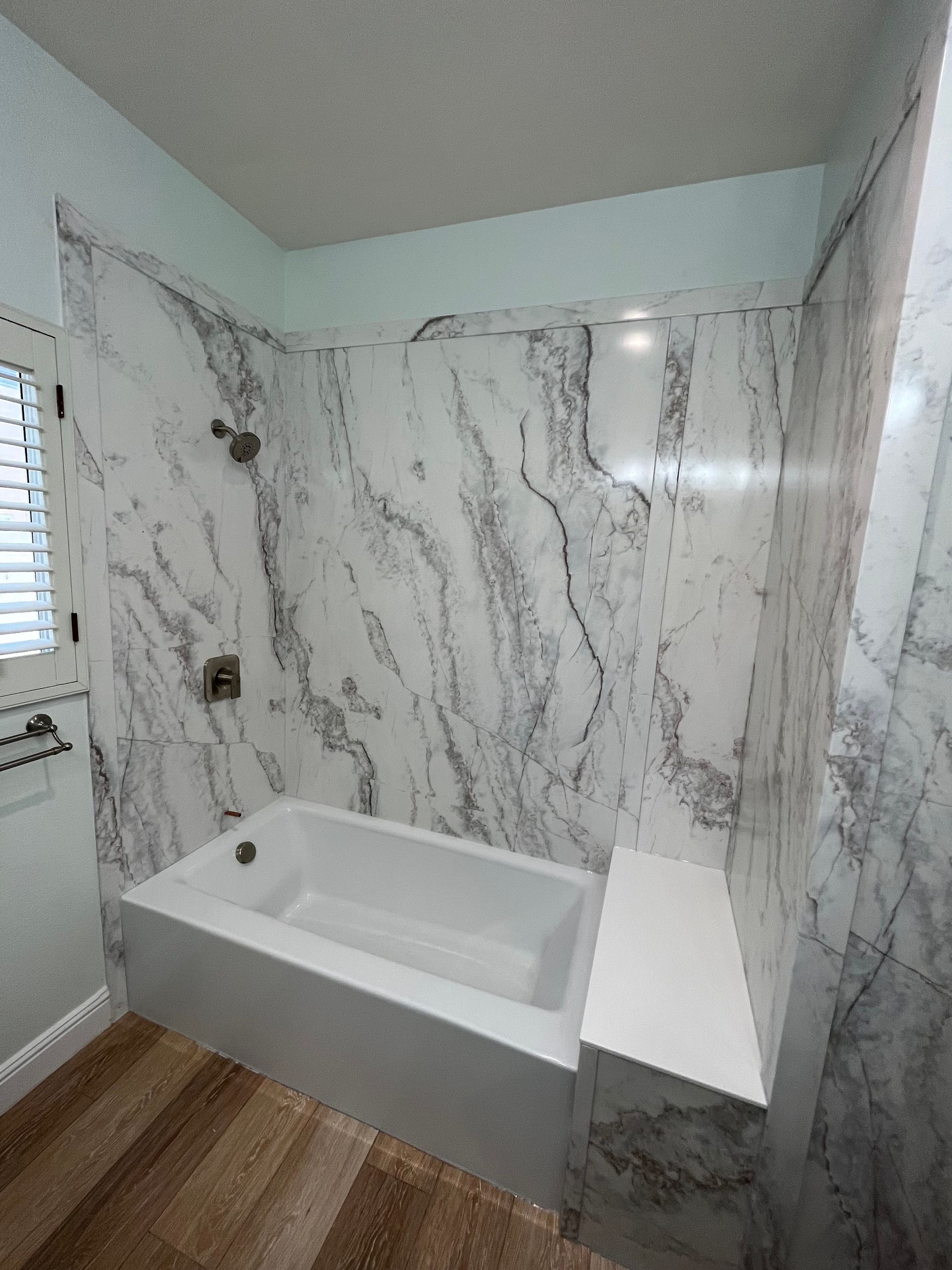 A bathroom with marble walls and a bathtub.