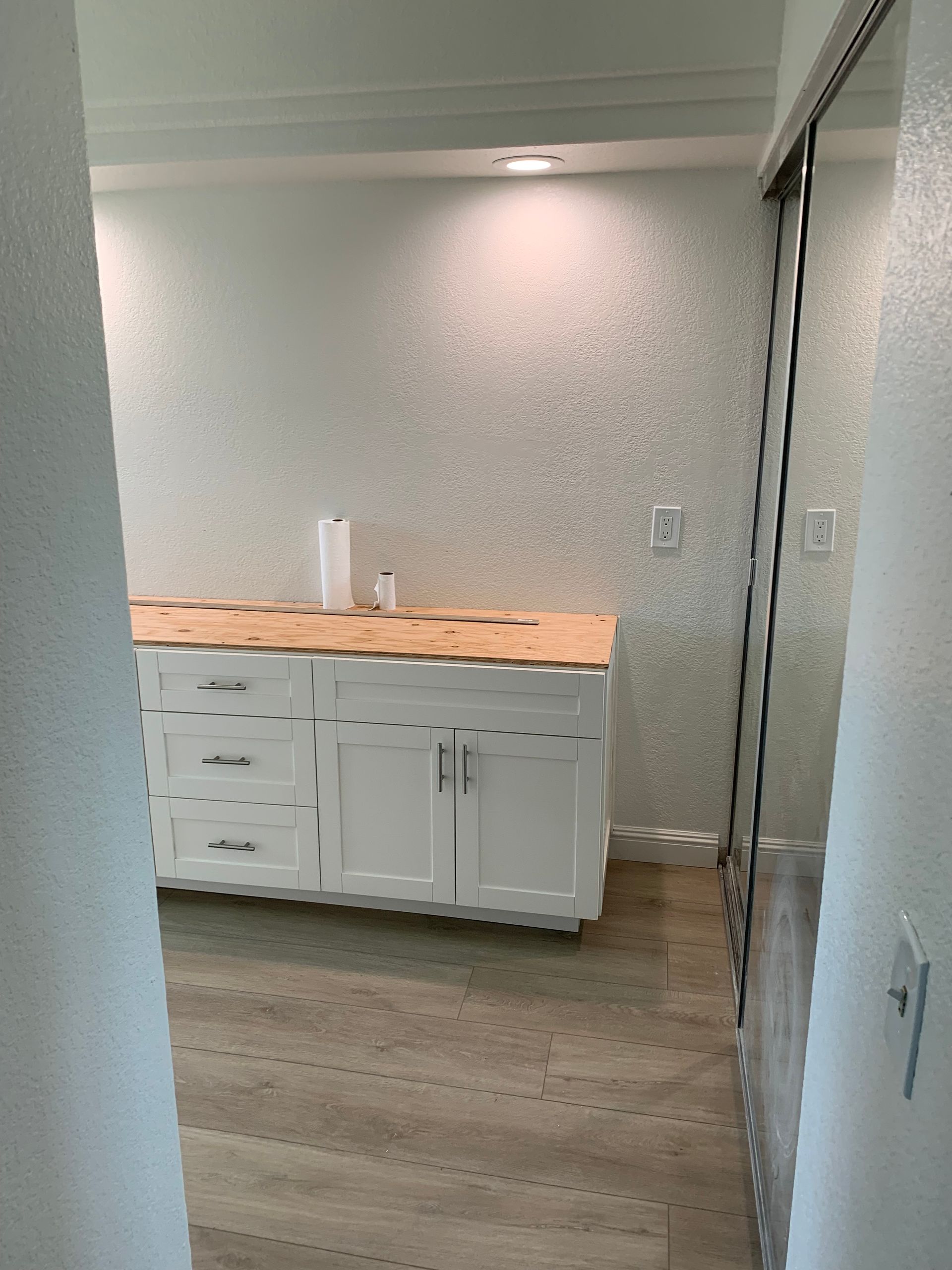 A kitchen with white cabinets and a wooden counter top