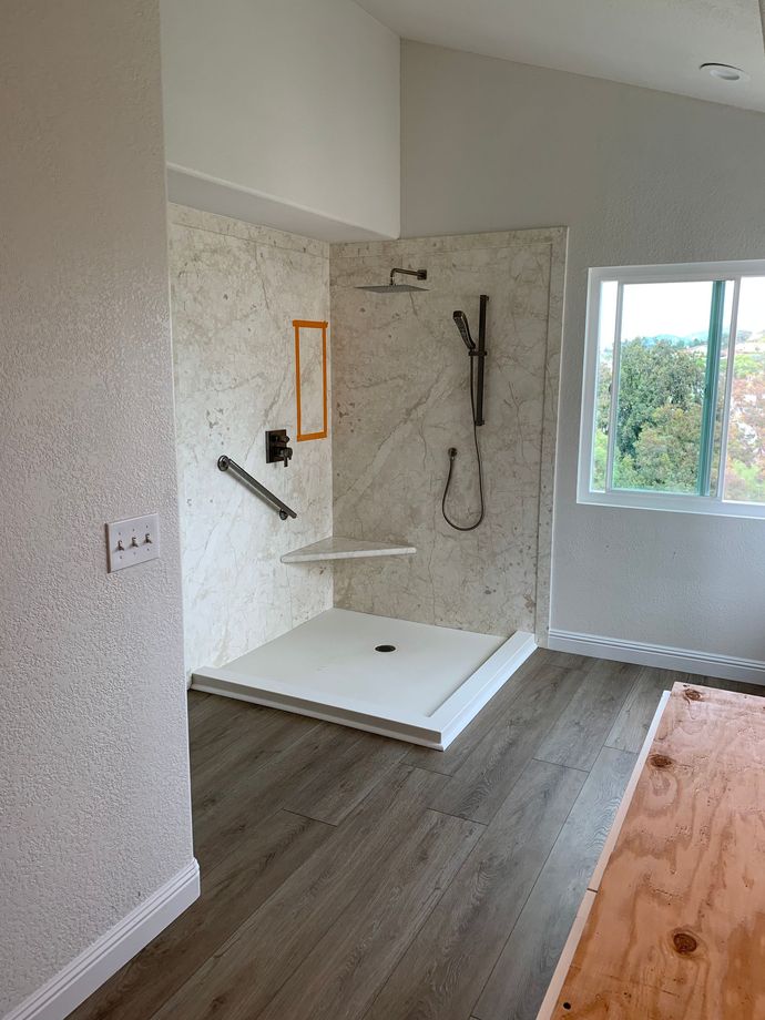 A bathroom with a walk in shower and a window.