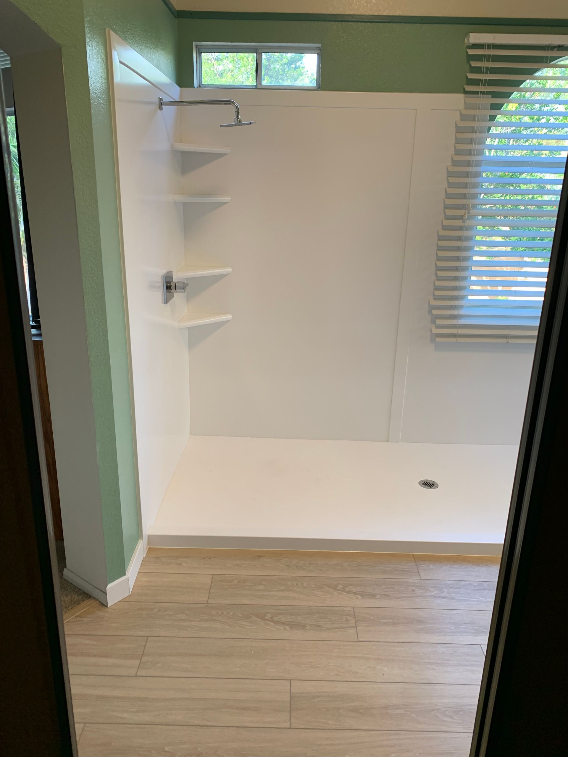 A bathroom with a walk in shower and a window.