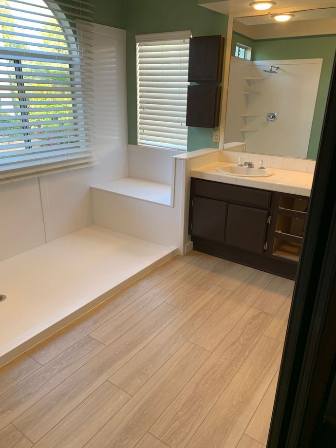 A bathroom with a sink , shower , and mirror.