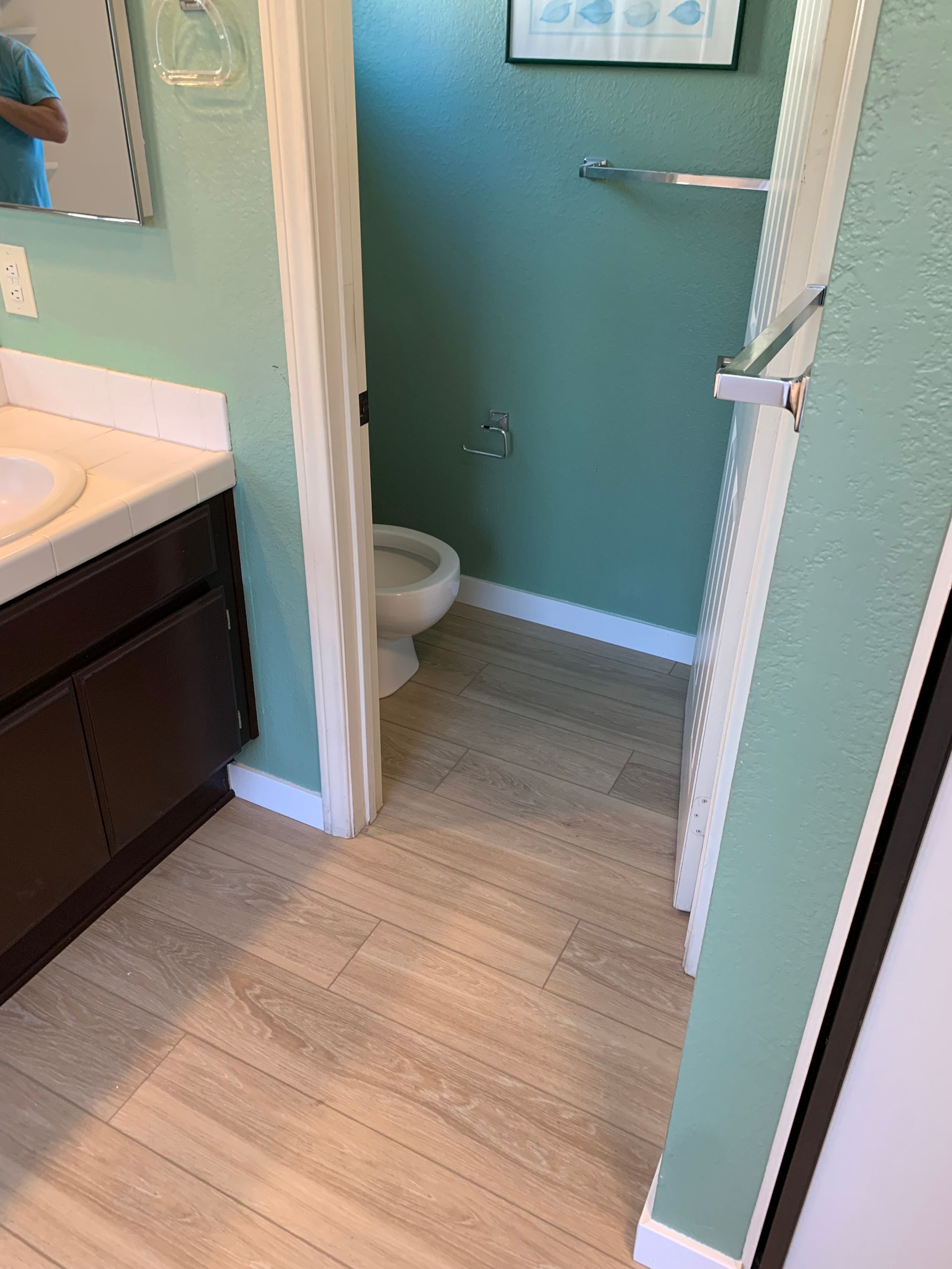 A bathroom with a toilet , sink and mirror.