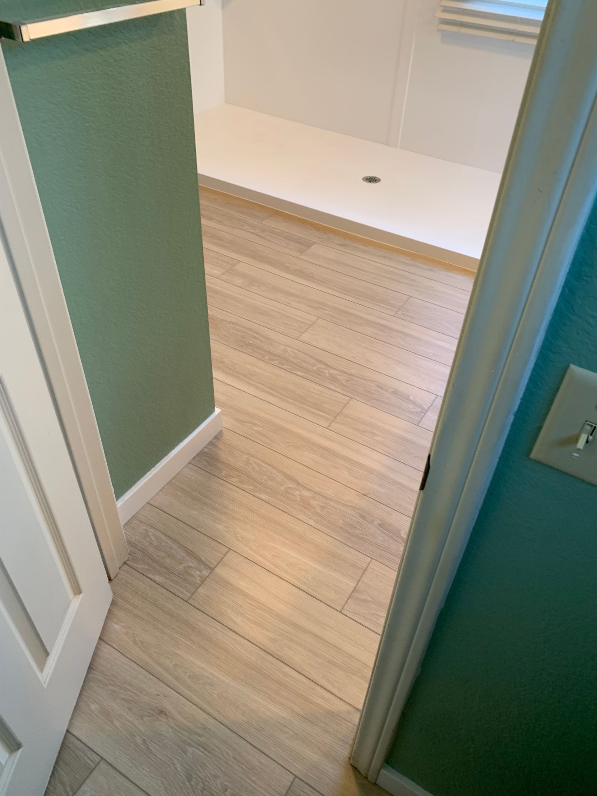 A bathroom with a wooden floor and a shower stall.