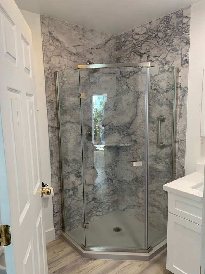 A bathroom with a walk in shower and a sink.