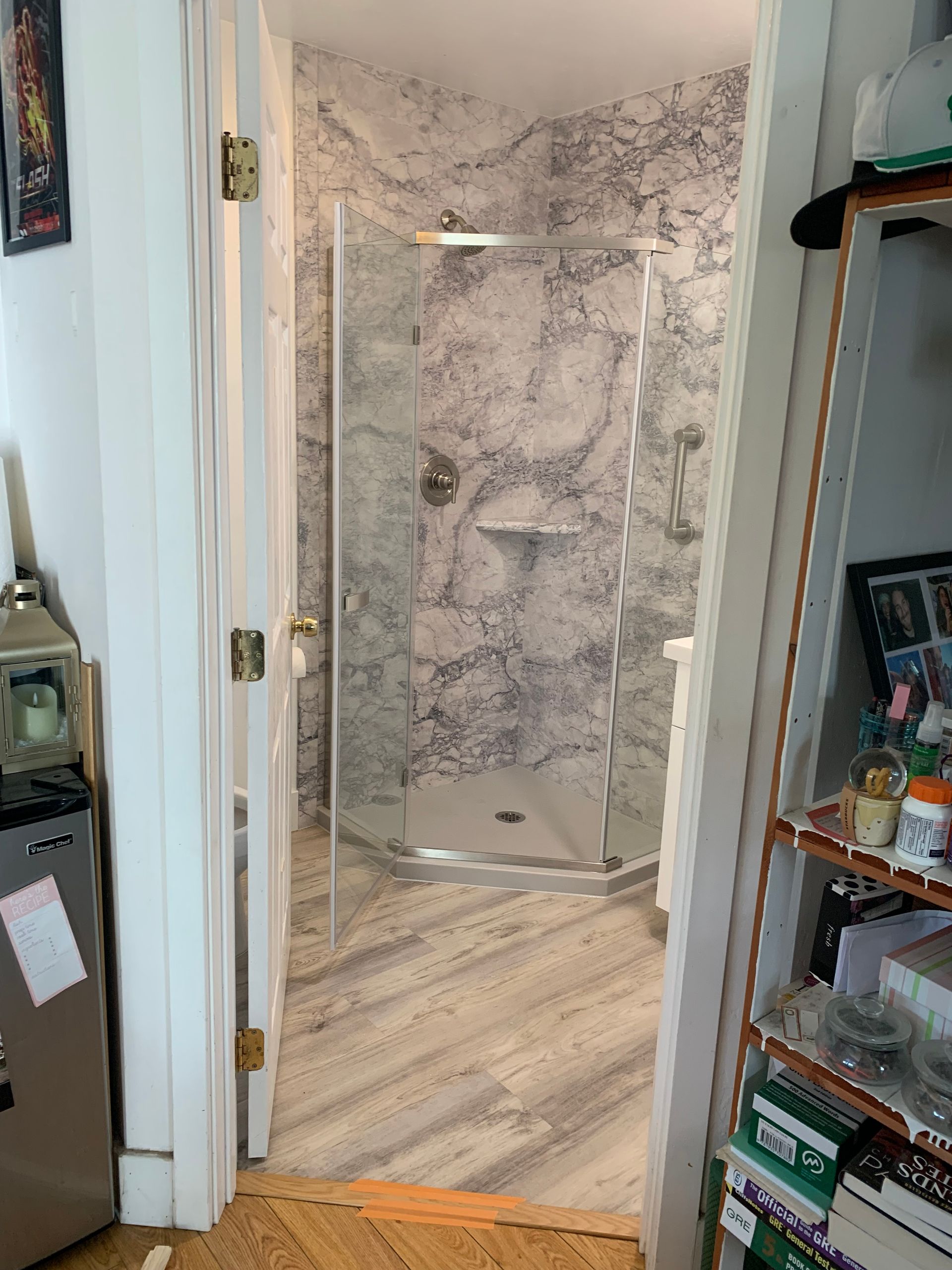 A bathroom with a walk in shower and a marble wall.