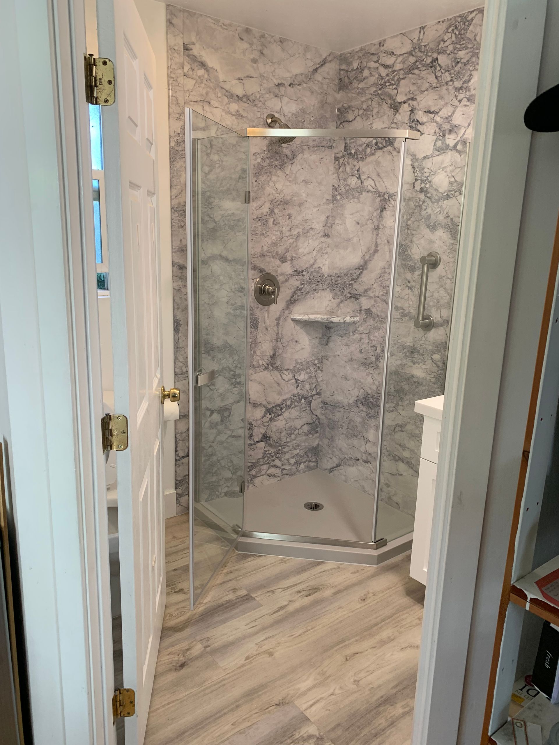 A bathroom with a walk in shower and marble walls.