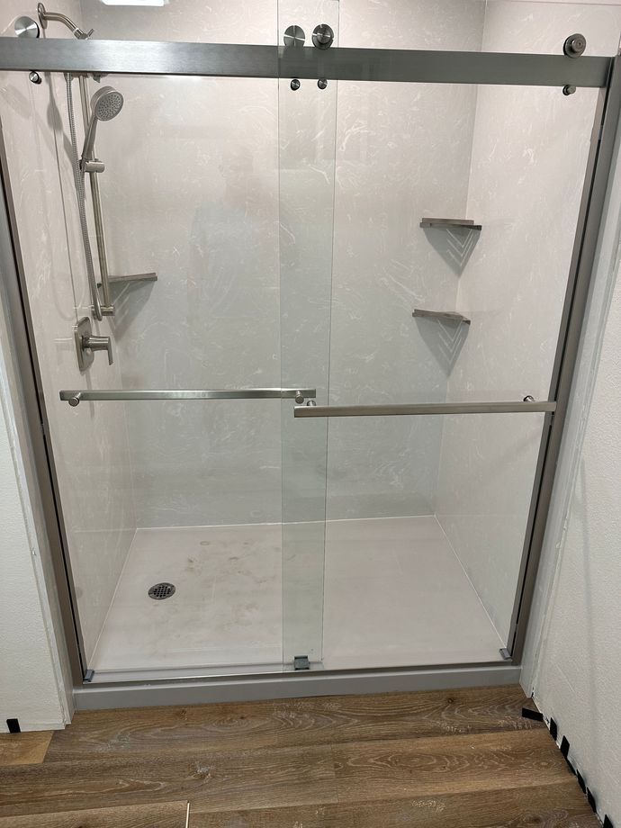 A bathroom with a sliding glass shower door and a shower head.