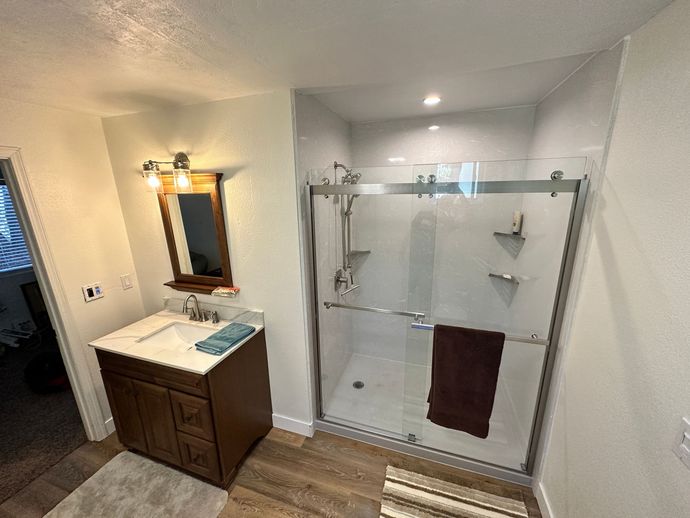 A bathroom with a sink , mirror , and walk in shower.