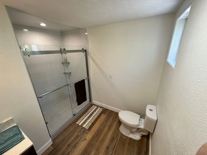 A bathroom with a toilet , shower and window.