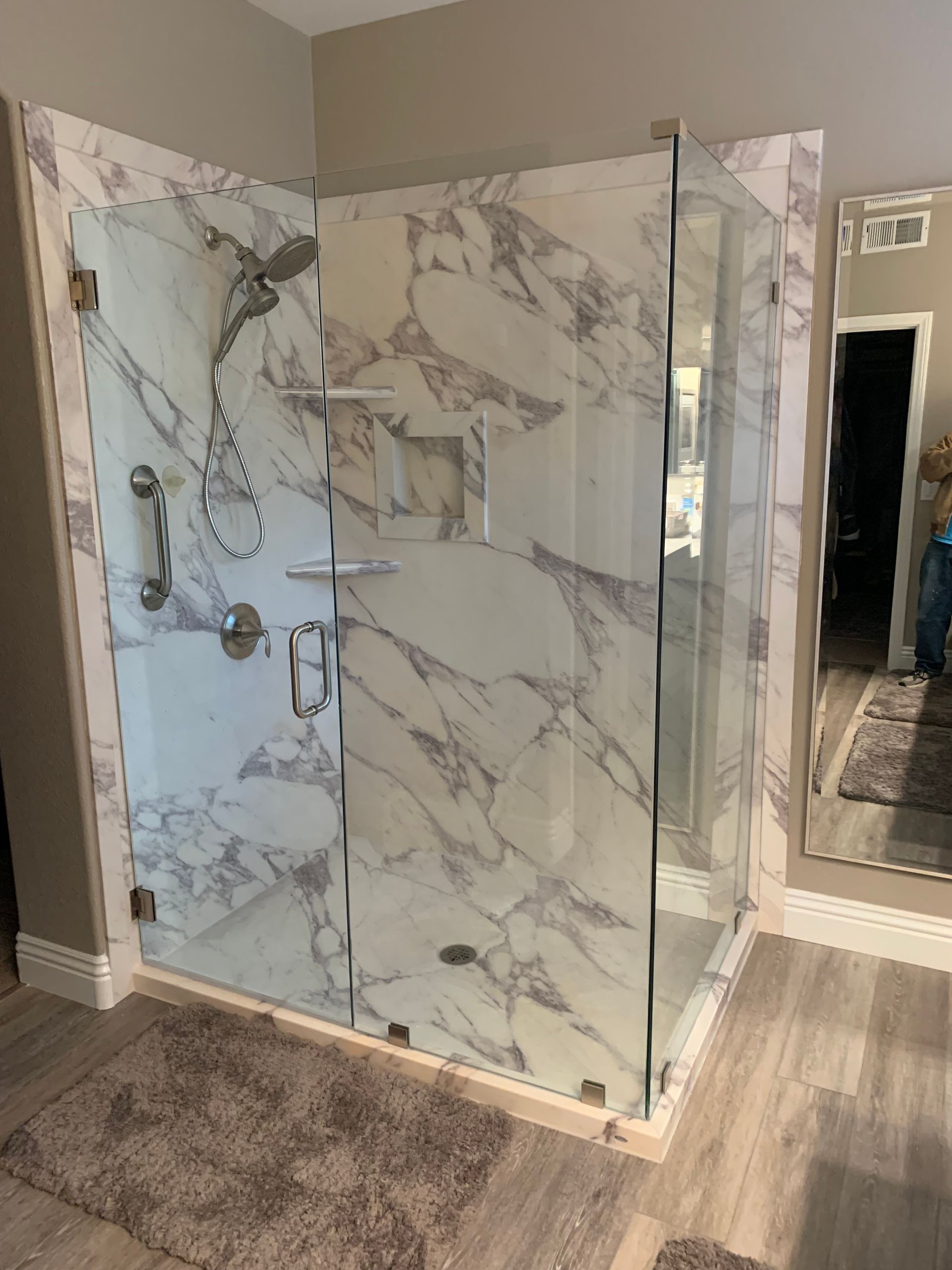 A bathroom with a walk in shower and marble walls.