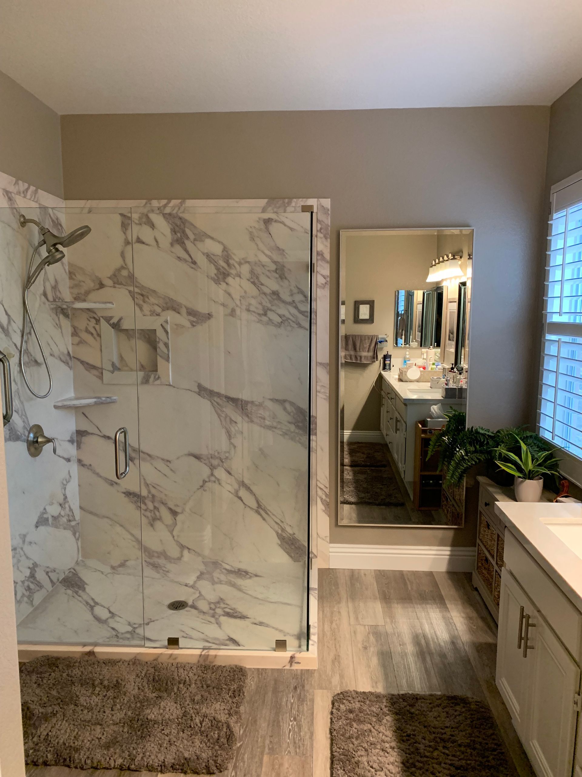 A bathroom with a walk in shower and a large mirror.