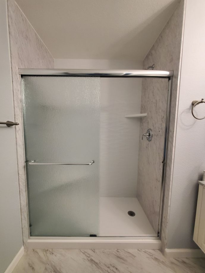 A bathroom with a sliding glass shower door and a sink.