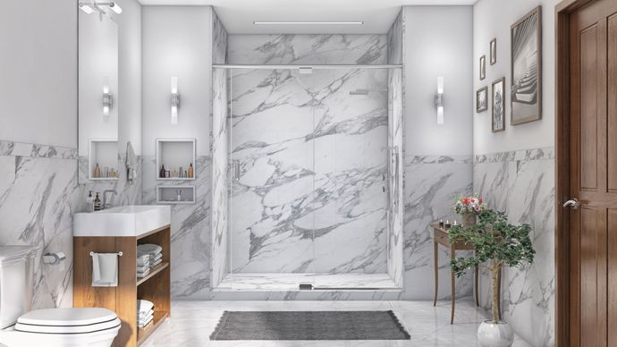 A bathroom with marble walls , a toilet , sink and shower.