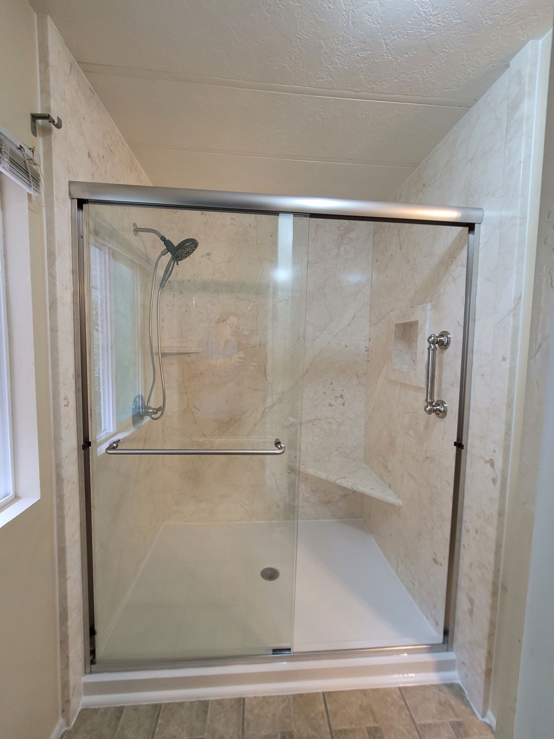 A bathroom with a sliding glass shower door and a window.