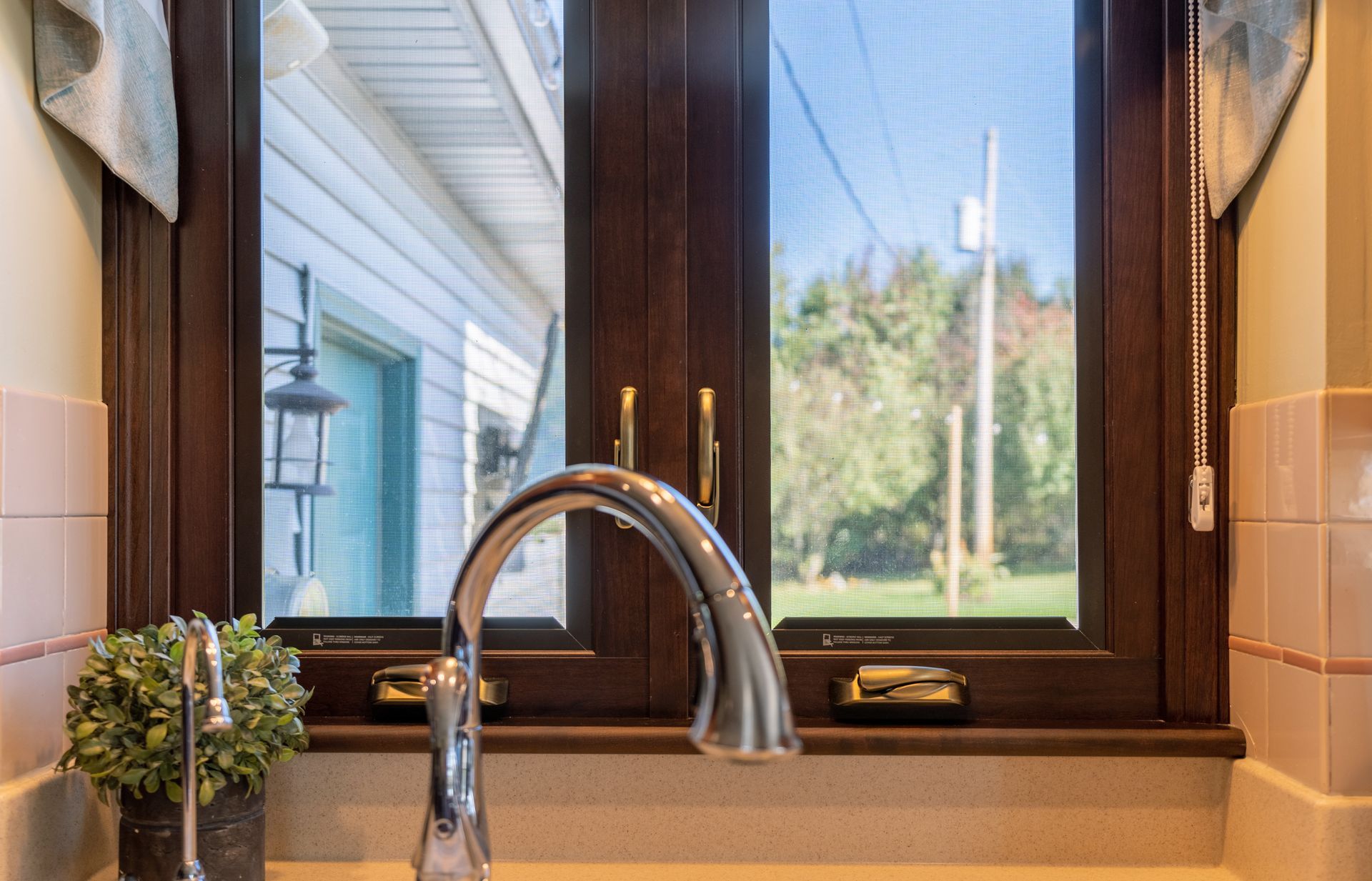 A kitchen sink with a faucet and a window in the background.