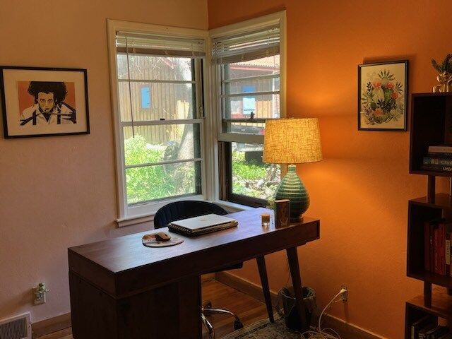 A desk with a laptop on it in a room with orange walls