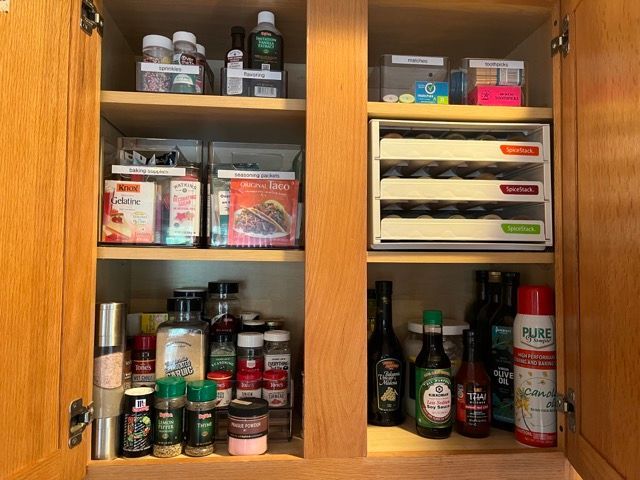 A kitchen cabinet filled with lots of spices and bottles.