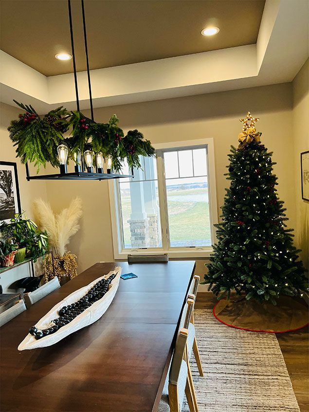 A dining room table with a christmas tree in the background.