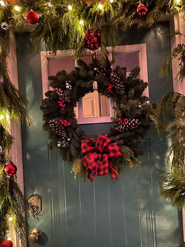 A christmas wreath is hanging on a blue door.