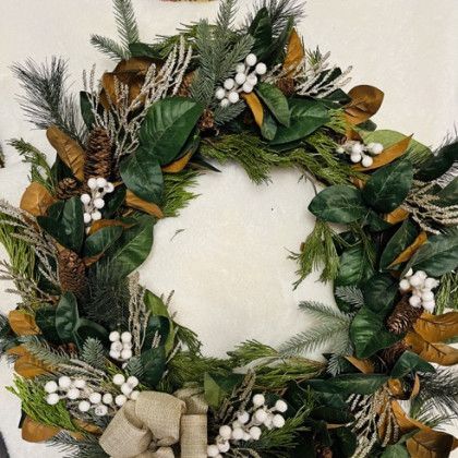 A close up of a christmas wreath with leaves and berries on a white surface.