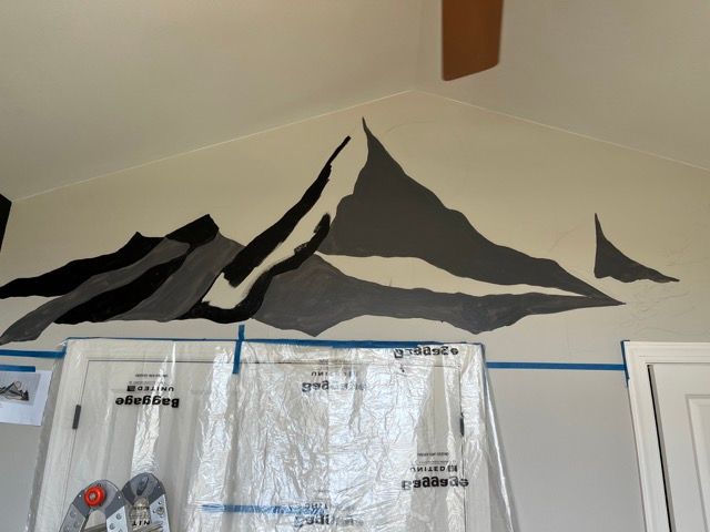 A painting of a mountain is being painted on a wall