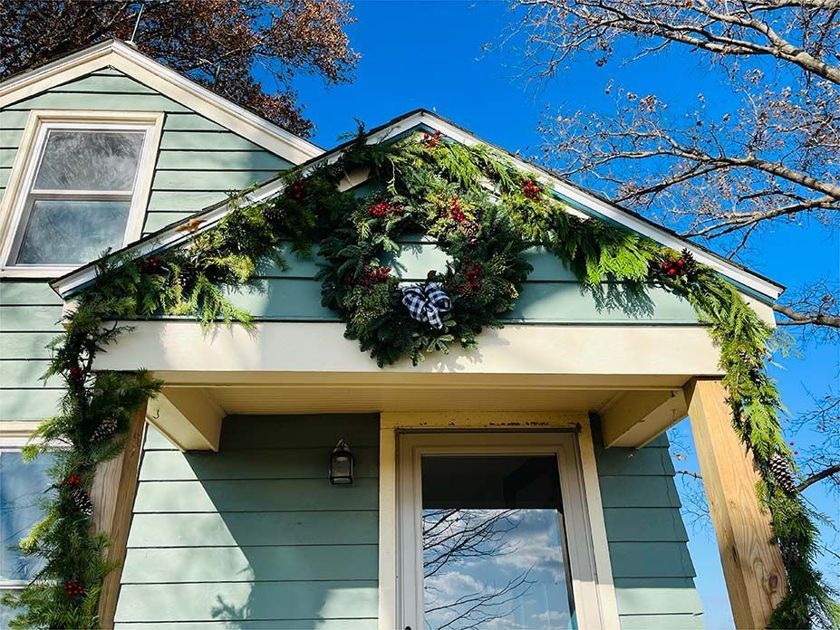 A blue house with a christmas wreath on the porch.