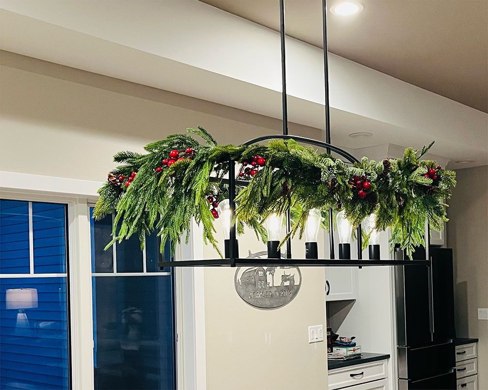 A kitchen with a chandelier hanging from the ceiling decorated for christmas.