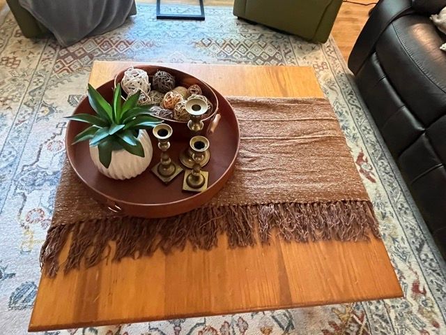 A wooden coffee table with a bowl of decorations on top of it.