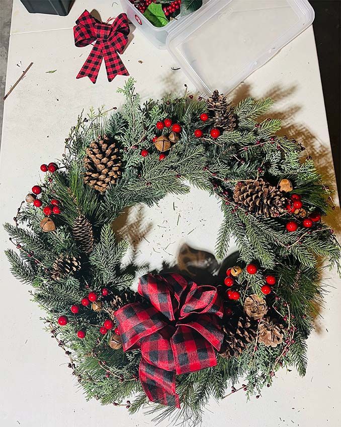A christmas wreath with pine cones and red berries on a table