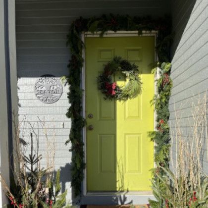 A yellow door with a christmas wreath on it.