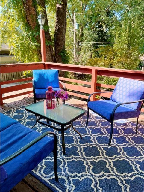 A deck with blue furniture and a rug