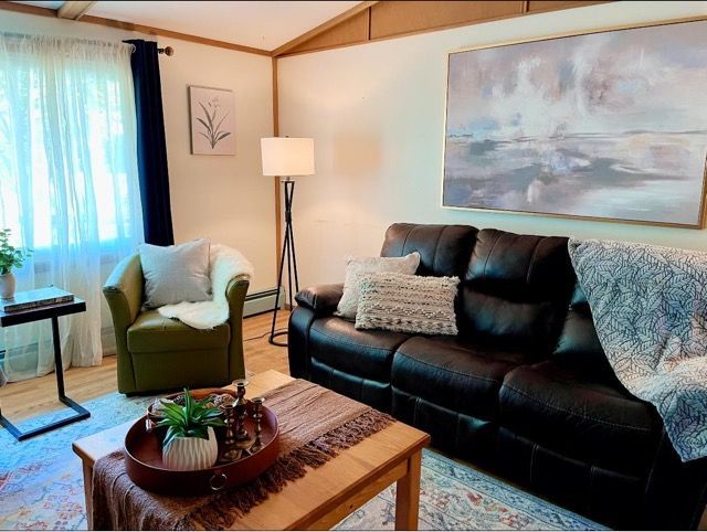 A living room with a couch , chair , coffee table and painting on the wall.
