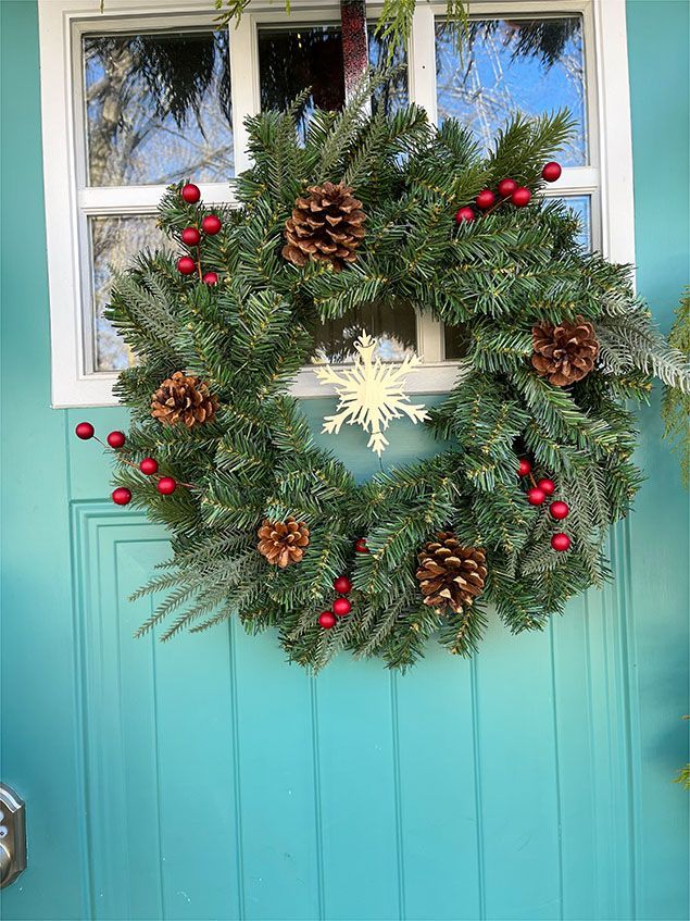 A christmas wreath is hanging on a blue door.
