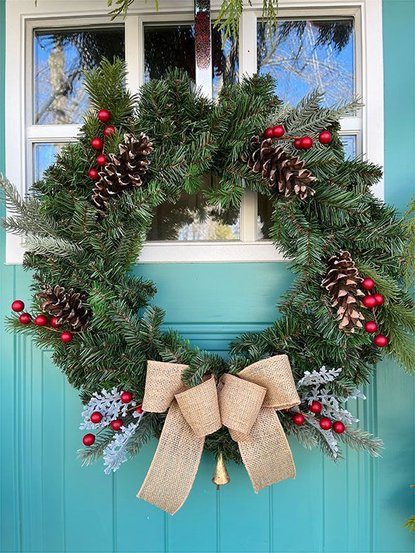 A christmas wreath is hanging on a blue door.